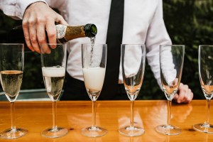 Close-up of a Kitsap Bartending Services Bartender pouring glasses of champagne into flute glasses