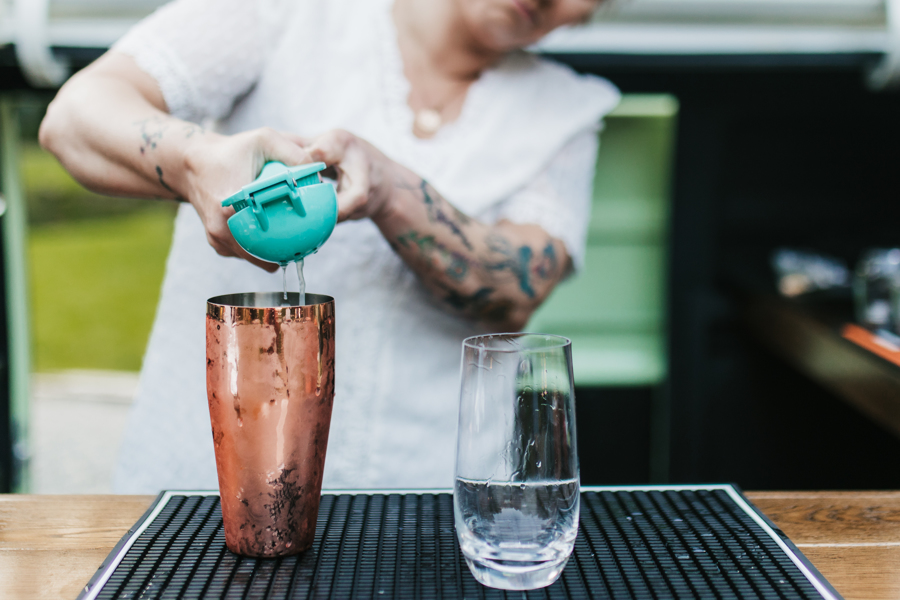 bartender squeezing citrus into a cocktail shaker