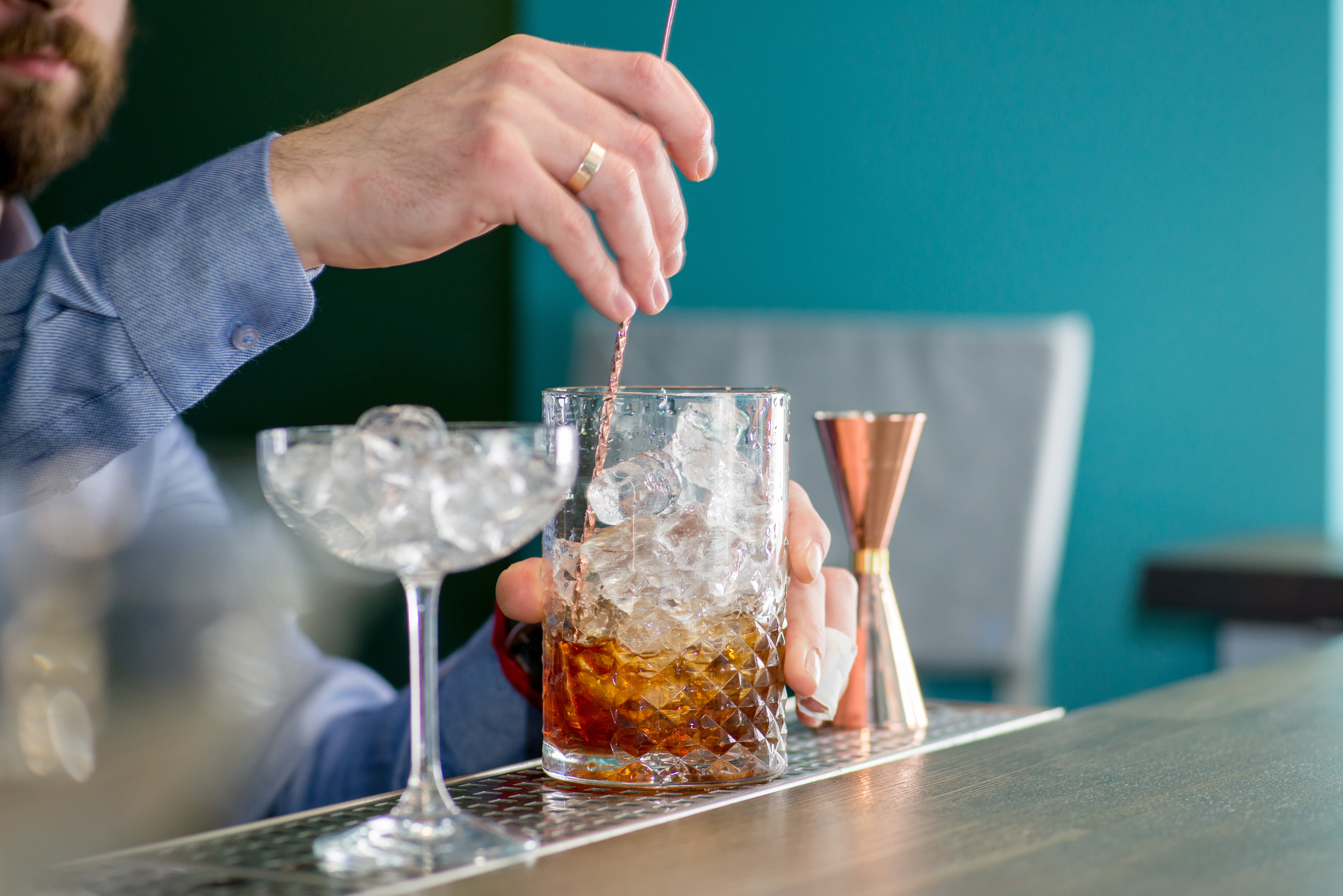 mobile bartender using a bar spoon with a mixing glass