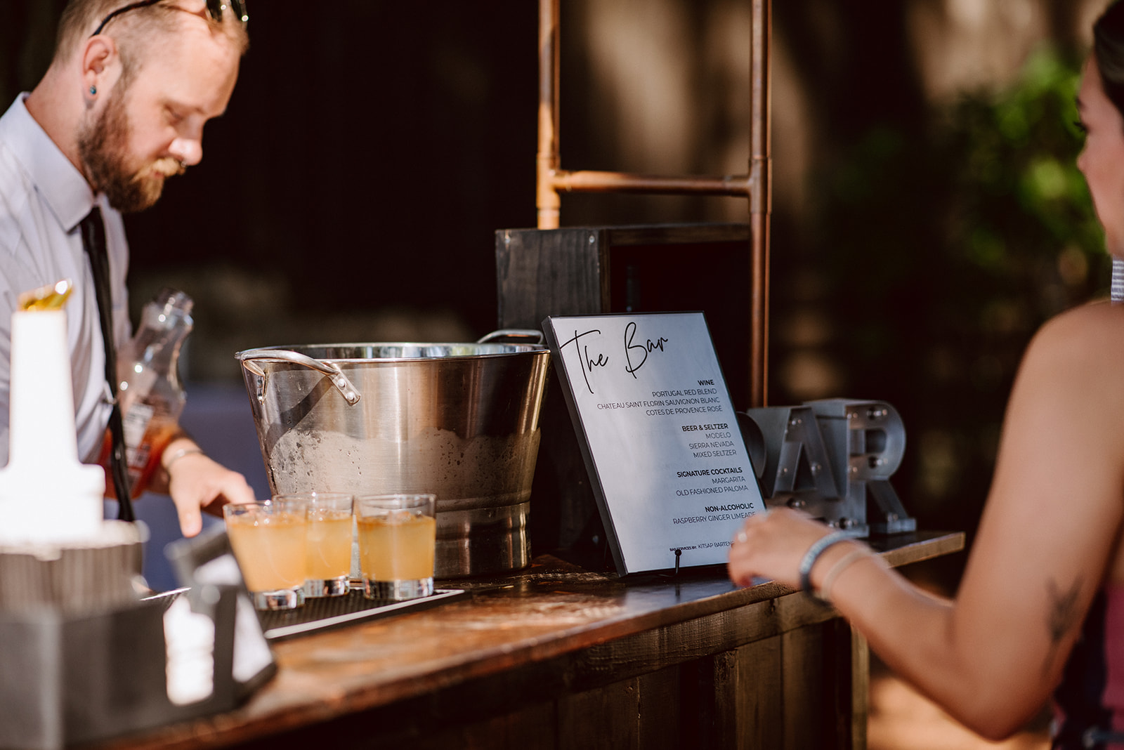 bartender lining up drinks on a black bar mat