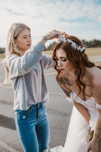 AllieKay Hair pinning hair of the model for the styled shoot in front of a vintage airplane in Gig Harbor